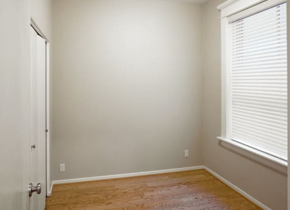 a bedroom with a wooden floor and a window and a door