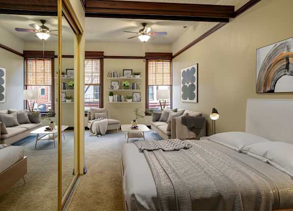 A bedroom with a large bed and a living area with a couch and chairs.