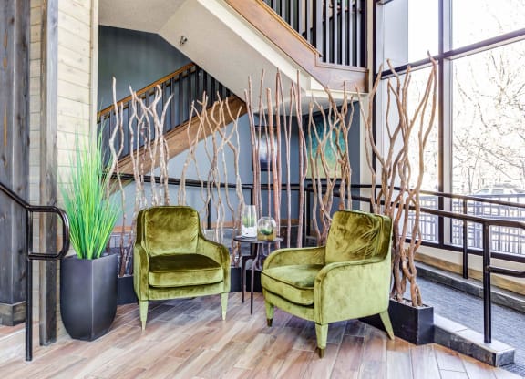 two green chairs in a lobby with a staircase in the background