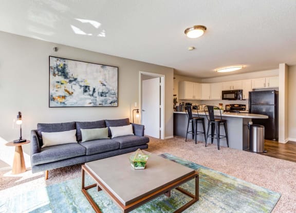 a living room with a couch coffee table and a kitchen in the background