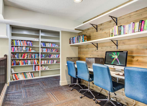 a library with a computer desk and three blue chairs