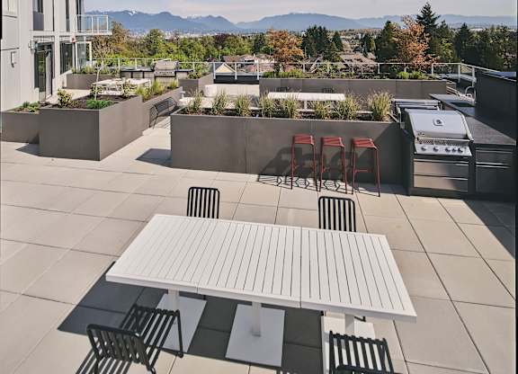 A white table and chairs are on a patio with a view of mountains.