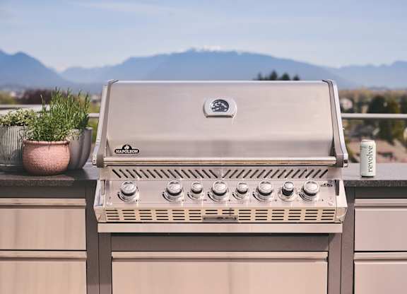 A gas grill on a balcony with a mountain view in the background.