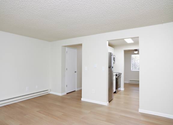 A white room with a door and a refrigerator.