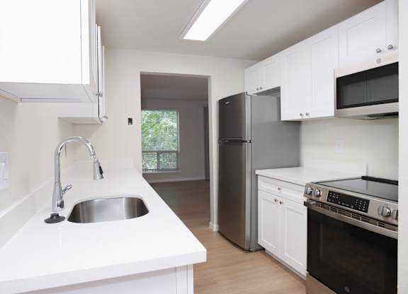 A kitchen with white cabinets and a stainless steel refrigerator.