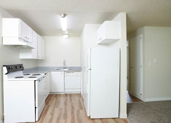 A white kitchen with a refrigerator on the right.