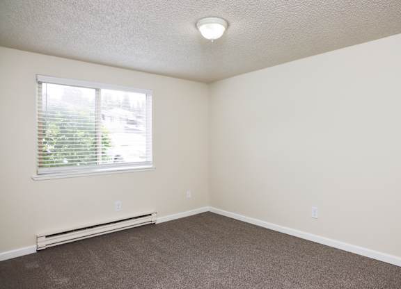 A room with a window and a heater on the floor.