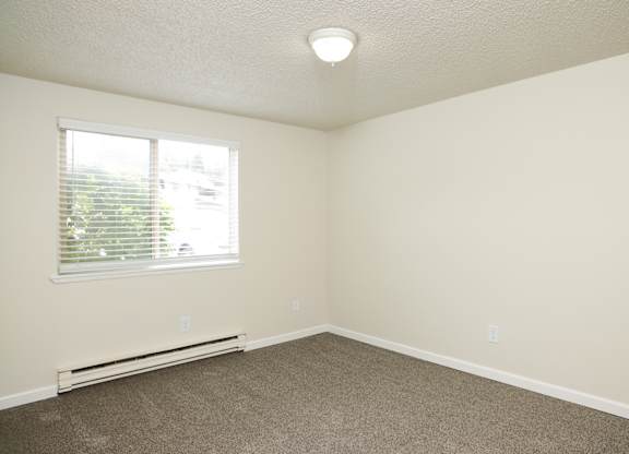 A room with a window and a heater on the floor.