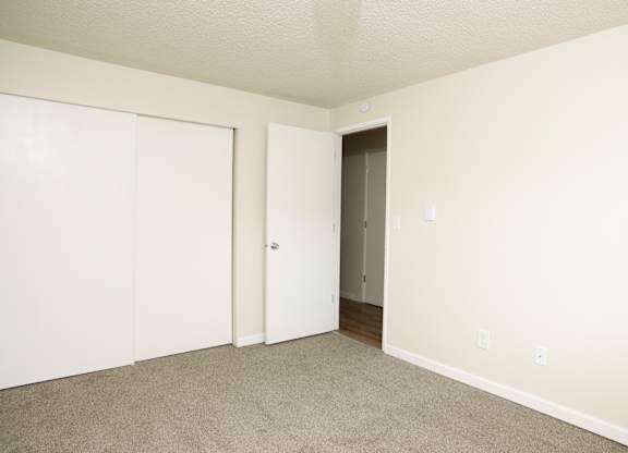 A room with a carpeted floor and two doors, one of which is open.