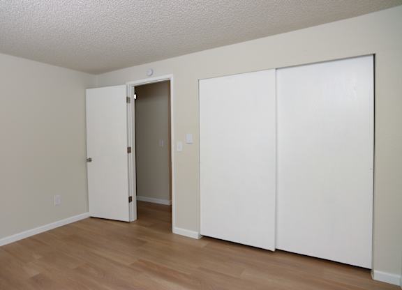 A room with a white door and two white closet doors.