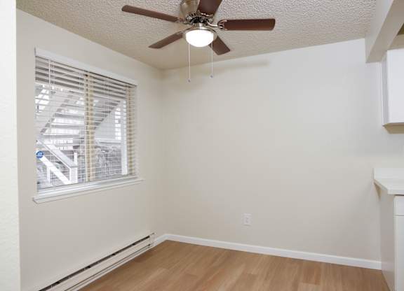 A room with a ceiling fan and a window with blinds.