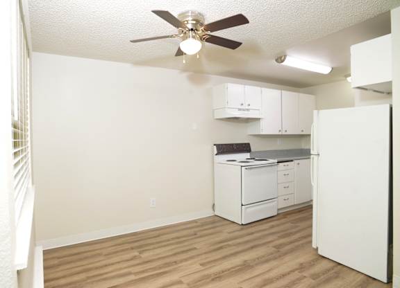 A room with a ceiling fan and a white refrigerator.
