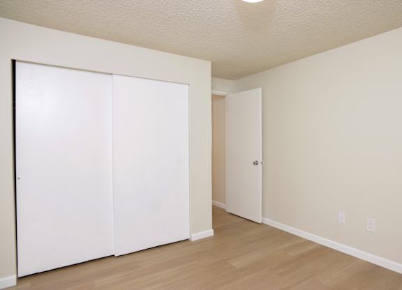 A room with a white closet and wooden floors.
