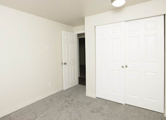 A white door is in a room with a carpeted floor.