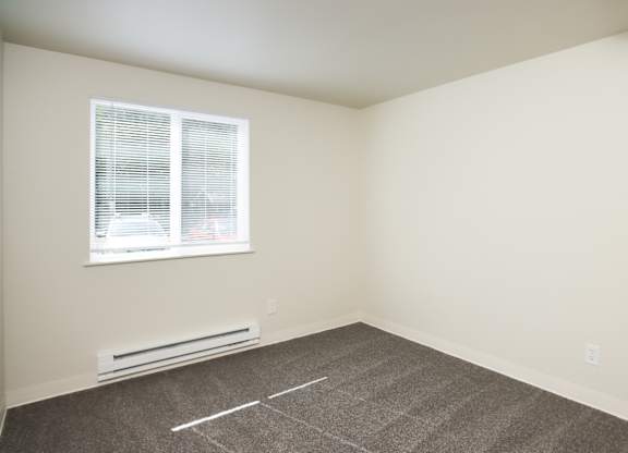 A room with a window and a heater on the floor.