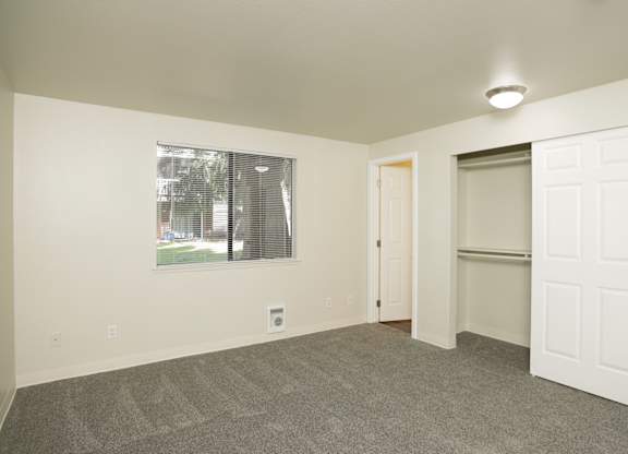 A room with a carpeted floor and a window with blinds.