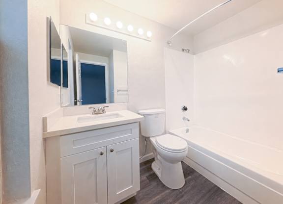 A white bathroom with a toilet, sink, and mirror.