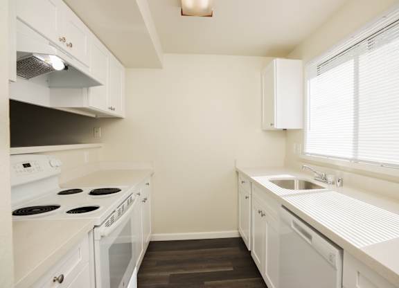 A white kitchen with a stove, oven, and sink.