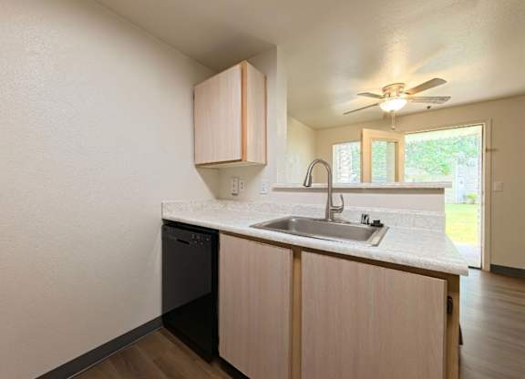 A kitchen with a black dishwasher and a white countertop.