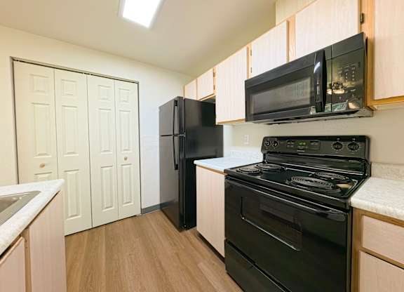 A kitchen with black appliances and wooden cabinets.