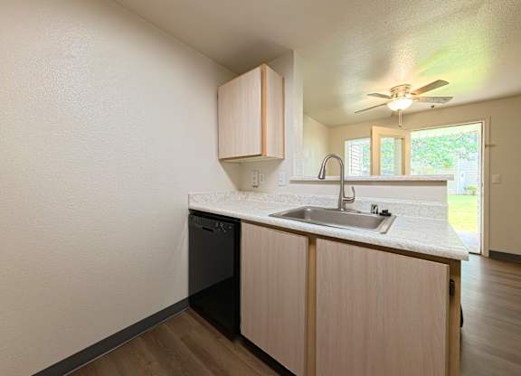 A kitchen with a black dishwasher and a white countertop.