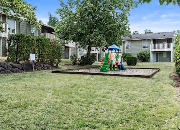 A playground with a slide and a green swing set.