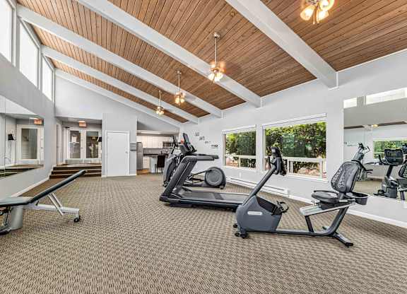 A gym with a variety of equipment including treadmills and weights.