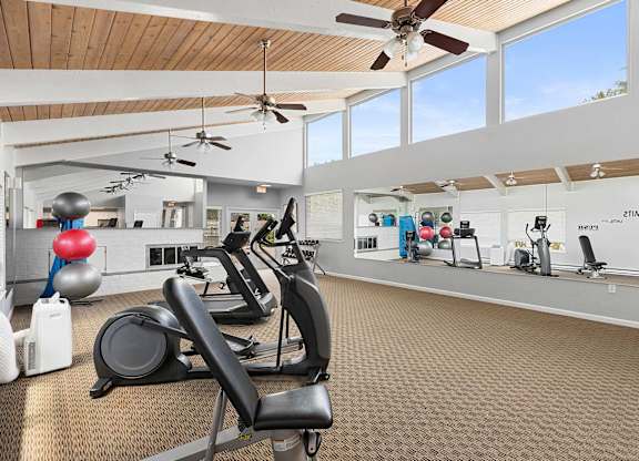 A gym with a variety of exercise equipment including treadmills, stationary bikes, and elliptical machines.