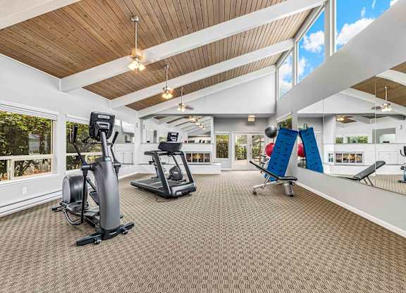 A spacious gym with a variety of equipment including treadmills, stationary bikes, and weight machines.