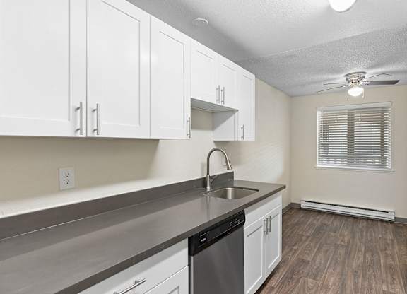 A kitchen with white cabinets and a stainless steel counter.
