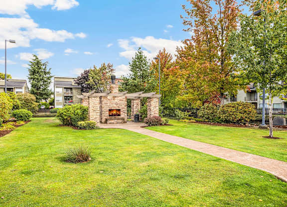 A sunny day in a well-kept garden with a stone fireplace.
