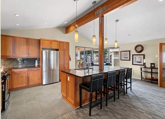 A kitchen with wooden cabinets and a large island with chairs.