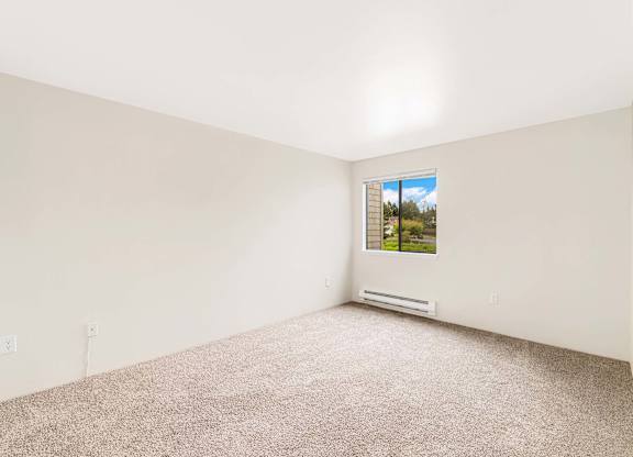 A room with a window and a carpeted floor.