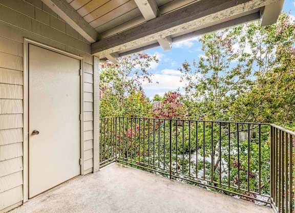 A balcony with a white door and a black railing.