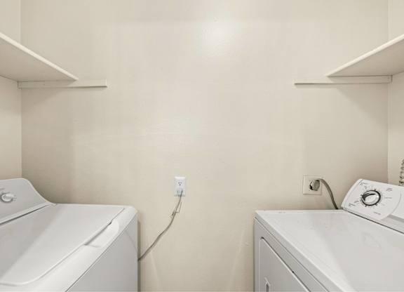 Two white washing machines in a laundry room.