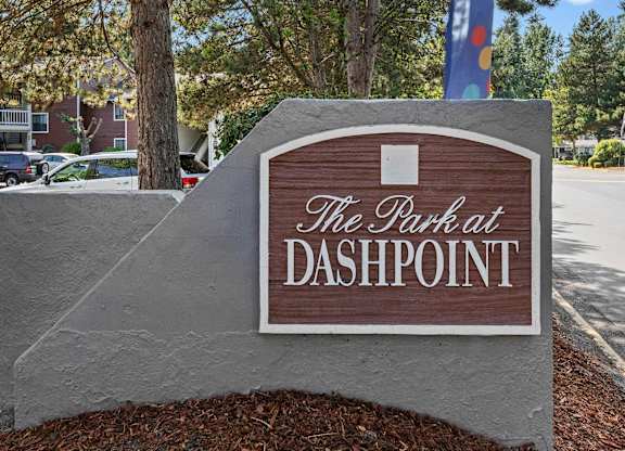 A sign that says "The Park at Dashpoint" is in front of a tree.
