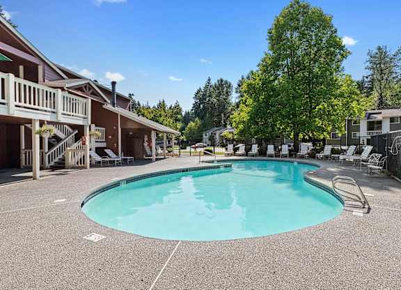 A large outdoor swimming pool surrounded by a fence and trees.