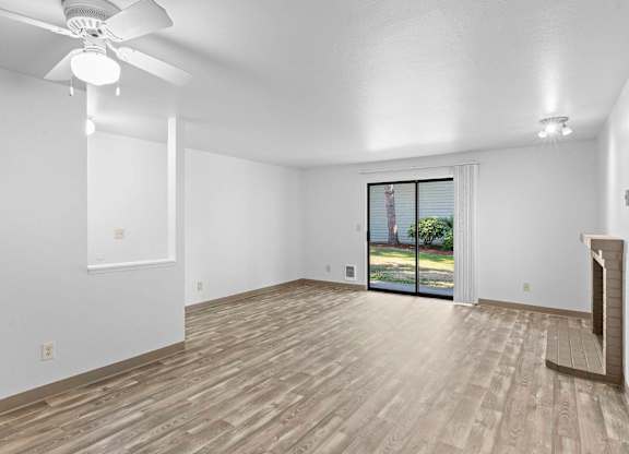 A room with a ceiling fan and sliding glass doors.