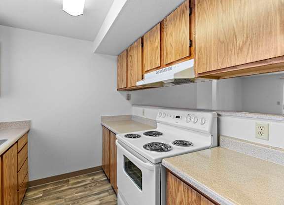 A kitchen with a white stove and wooden cabinets.