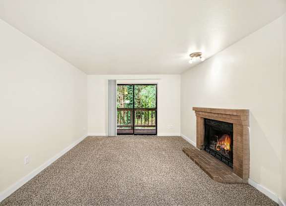 A room with a fireplace and a window with a view of trees.