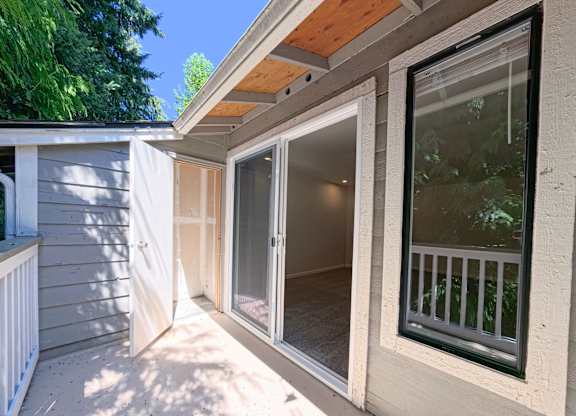 A sunny day with a balcony and sliding glass door.