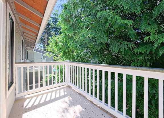 A white railing on a balcony with trees in the background.