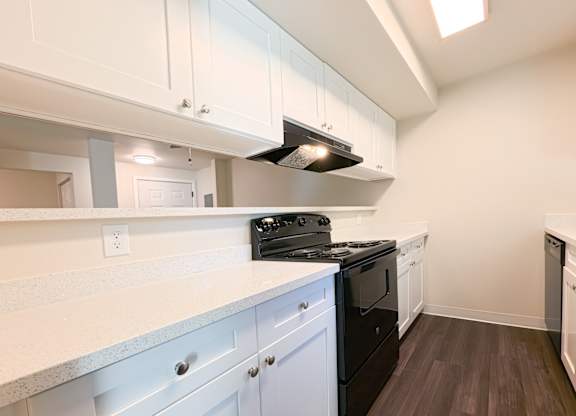 A kitchen with white cabinets and a black stove top oven.