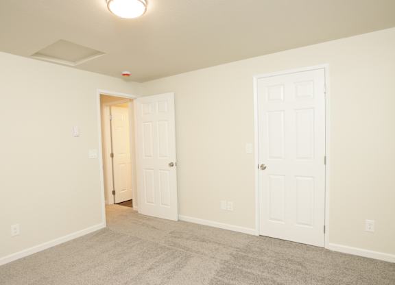 A room with two doors and carpeted floor.
