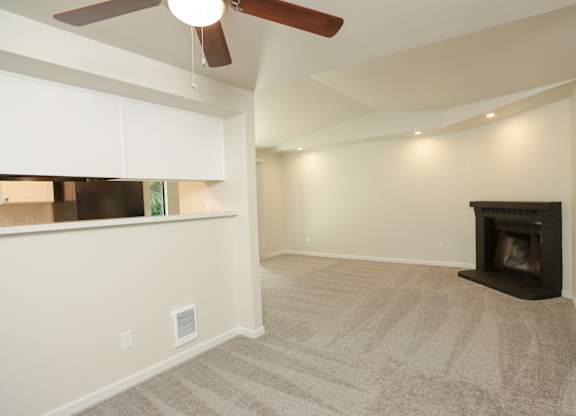 A living room with a fireplace and a ceiling fan.