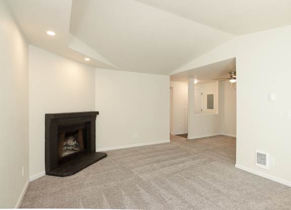 A living room with a fireplace and carpeted floor.