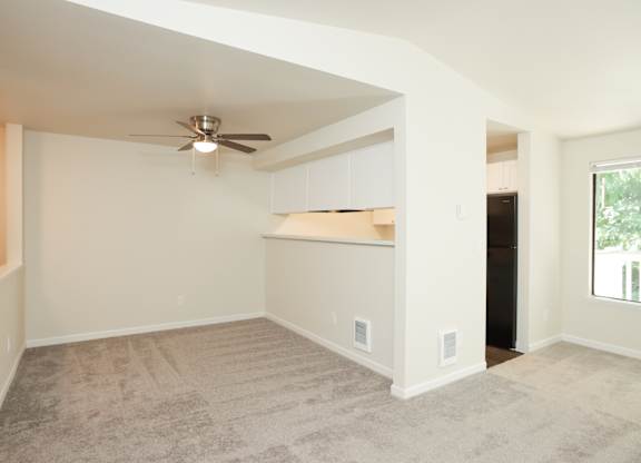 A room with a ceiling fan and carpeted floor.