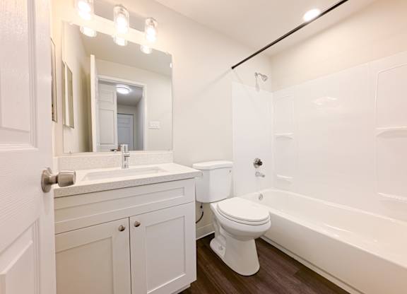 A white bathroom with a toilet, sink, and bathtub.