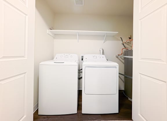 Two white washing machines in a small laundry room.