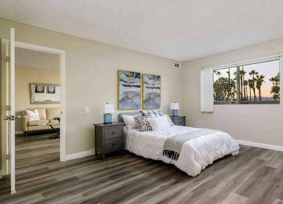A bedroom with a bed, nightstand, and a painting on the wall.